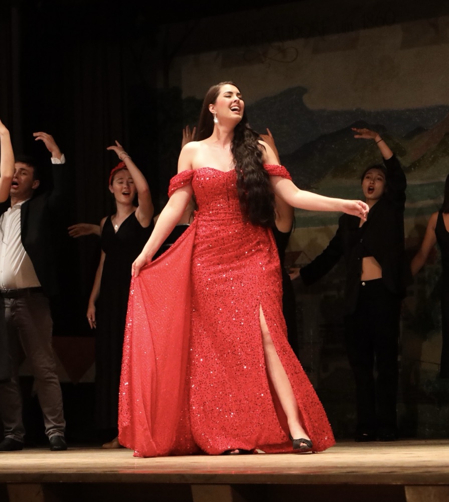 Opera Studio soprano in a red gown singing in concert with the ensemble