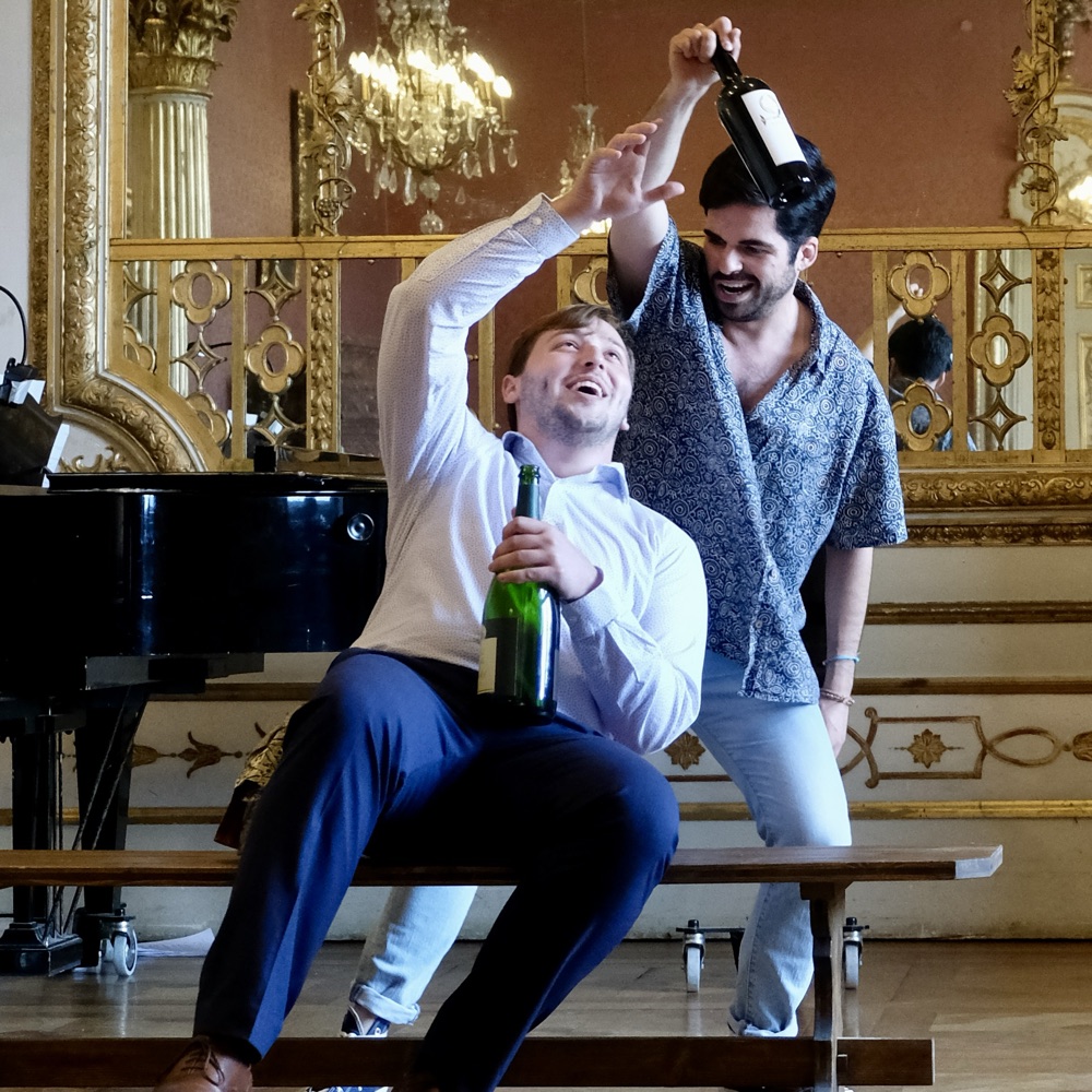 Two Opera Studio singers with champagne bottles in a rehearsal scene
